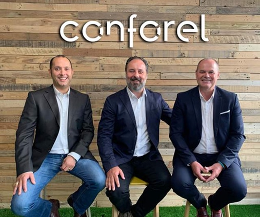 Dirigeants conforel : Trois hommes d'affaires souriants Trois hommes souriants en costume décontracté devant un mur en bois portant le logo « conforel ».