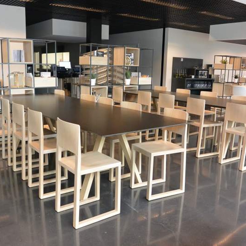 Salle de réunion moderne, mobilier design bois clair Salle de réunion moderne avec longue table noire et chaises minimalistes en bois clair. Étagères ouvertes style industriel en arrière-plan.