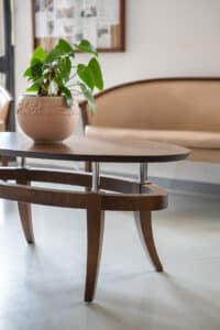 Table basse ovale bois sombre avec pot de fleur anthurium en céramique décorée, salon beige.